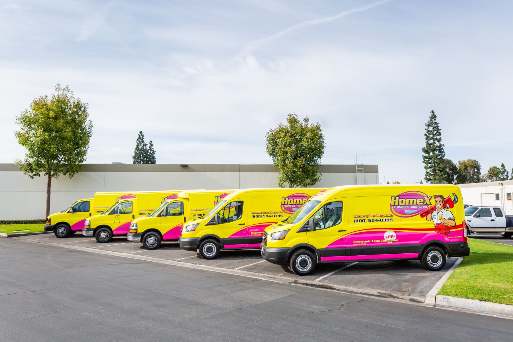 A row of Kahuna Comfort company vehicles that have pink and yellow colors with the logo