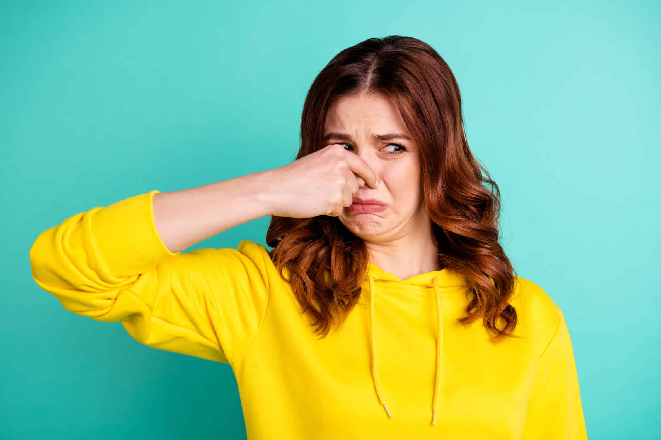 woman grimacing from garbage disposal smells